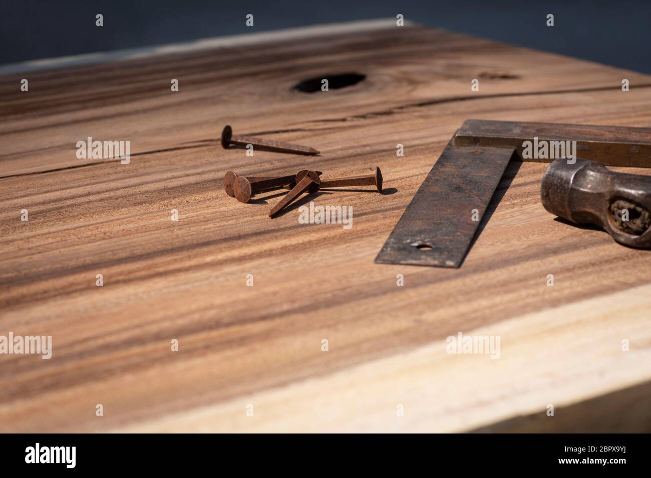 Un ancien outil de mesure, une partie d'un marteau et de vieux clous rouillés qui se posent sur une dalle de bois suar. Outils de menuiserie rétro vintage, bricolage Banque D'Images