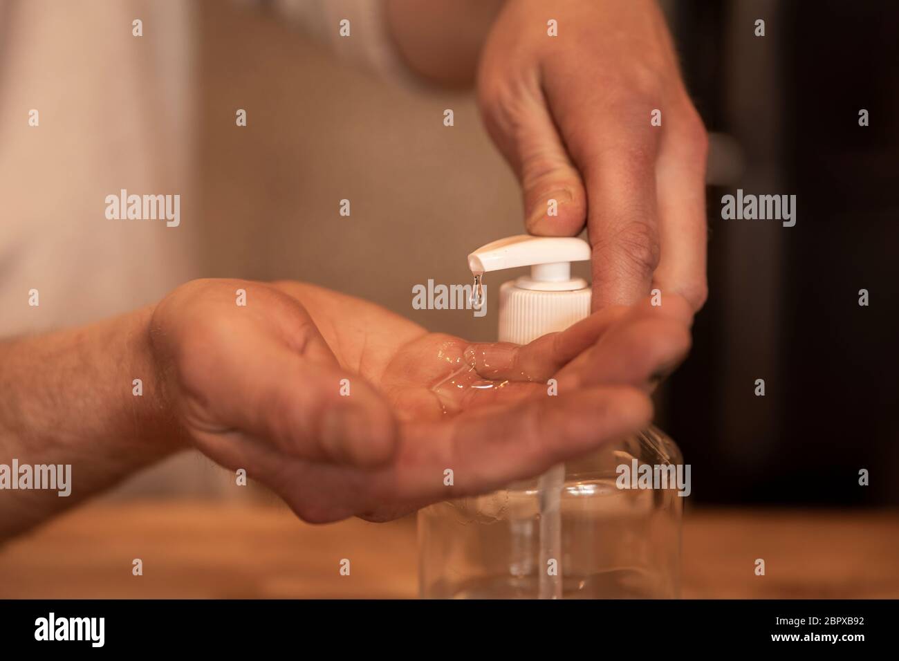 À l'aide d'un désinfectant pour les mains. Mains d'un homme utilisant des gouttes de desinfectant et l'appliquant sur ses mains pour se protéger et protéger les autres. Photo détaillée, bokeh ba Banque D'Images