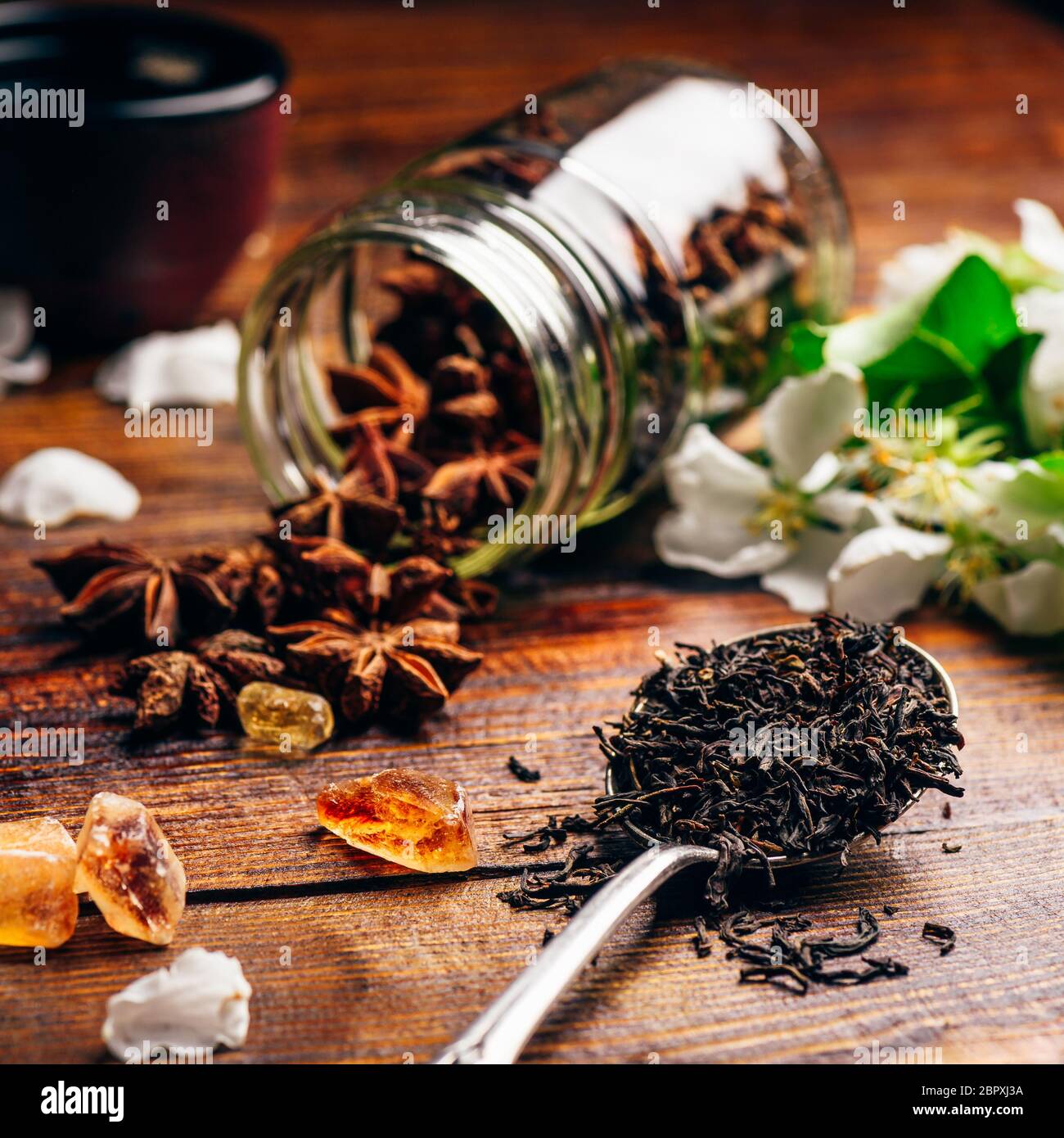 Cuillerée de thé, de sucre et d'Apple Fleurs, étoile d'anis éparpillés sur la table en bois. Banque D'Images