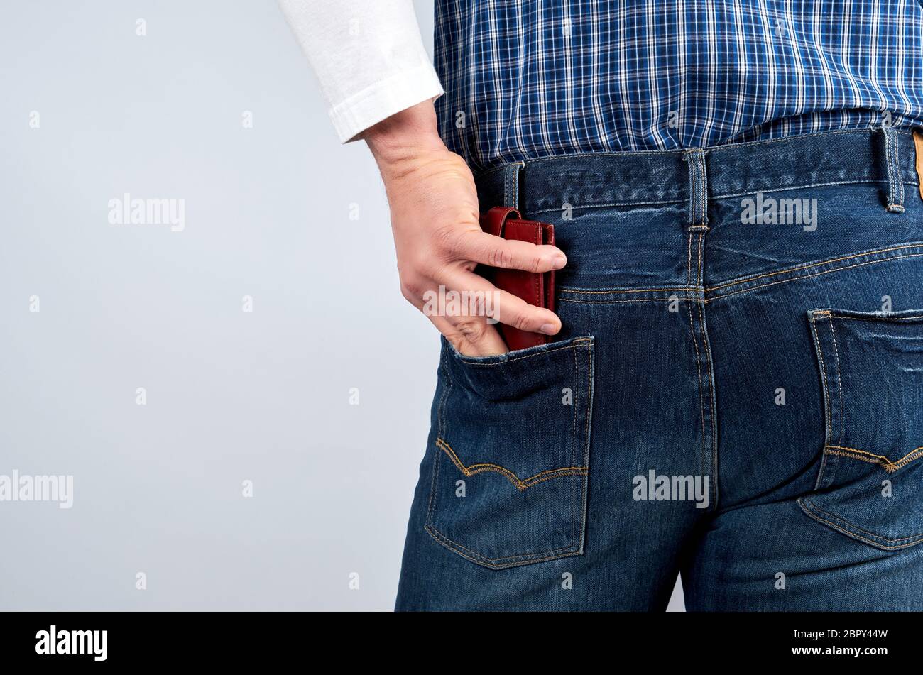 L'homme dans une chemise à carreaux bleu jeans et une pochette en cuir met dans sa poche arrière, fond blanc Banque D'Images