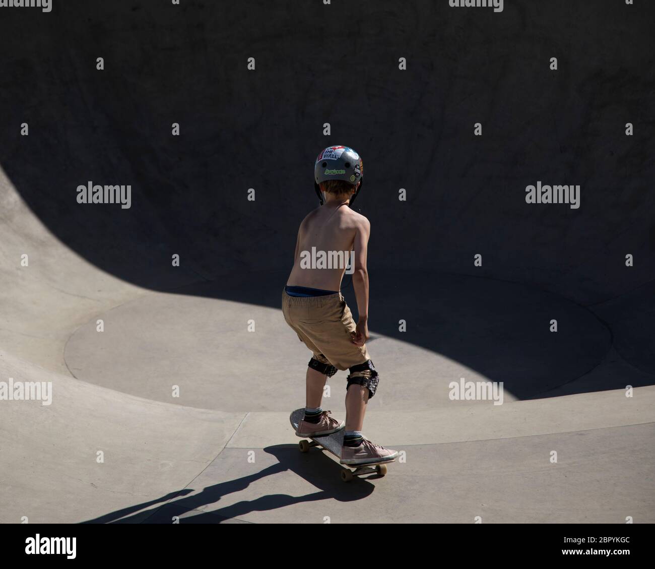 Un garçon sur un skateboard est sur le point d'entrer dans le bol dans un parc de skate Banque D'Images