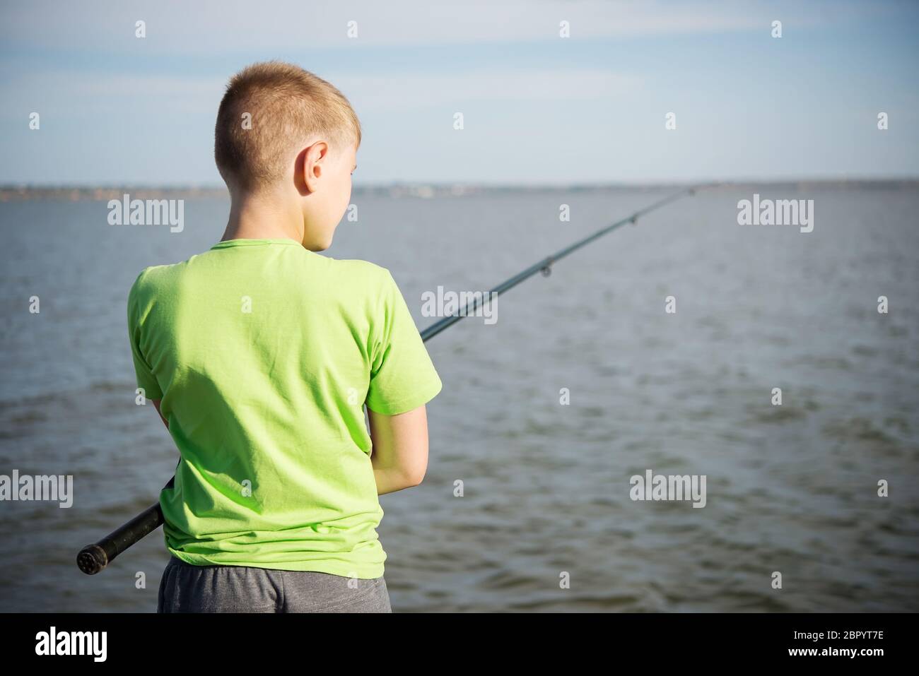 Garçon pêchant sur un lac en été. Vue de l'arrière Banque D'Images