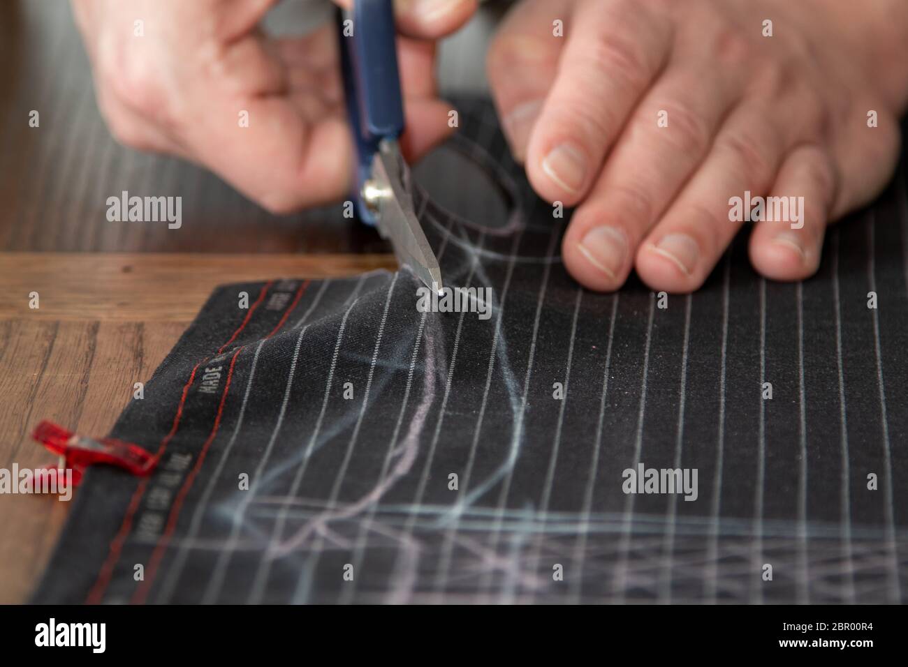 Tailleur les mains de couper le tissu à l'aide de ciseaux ou de ciseaux larges comme il suit les marques de craie du modèle, l'accent sélectif sur le tissu Banque D'Images