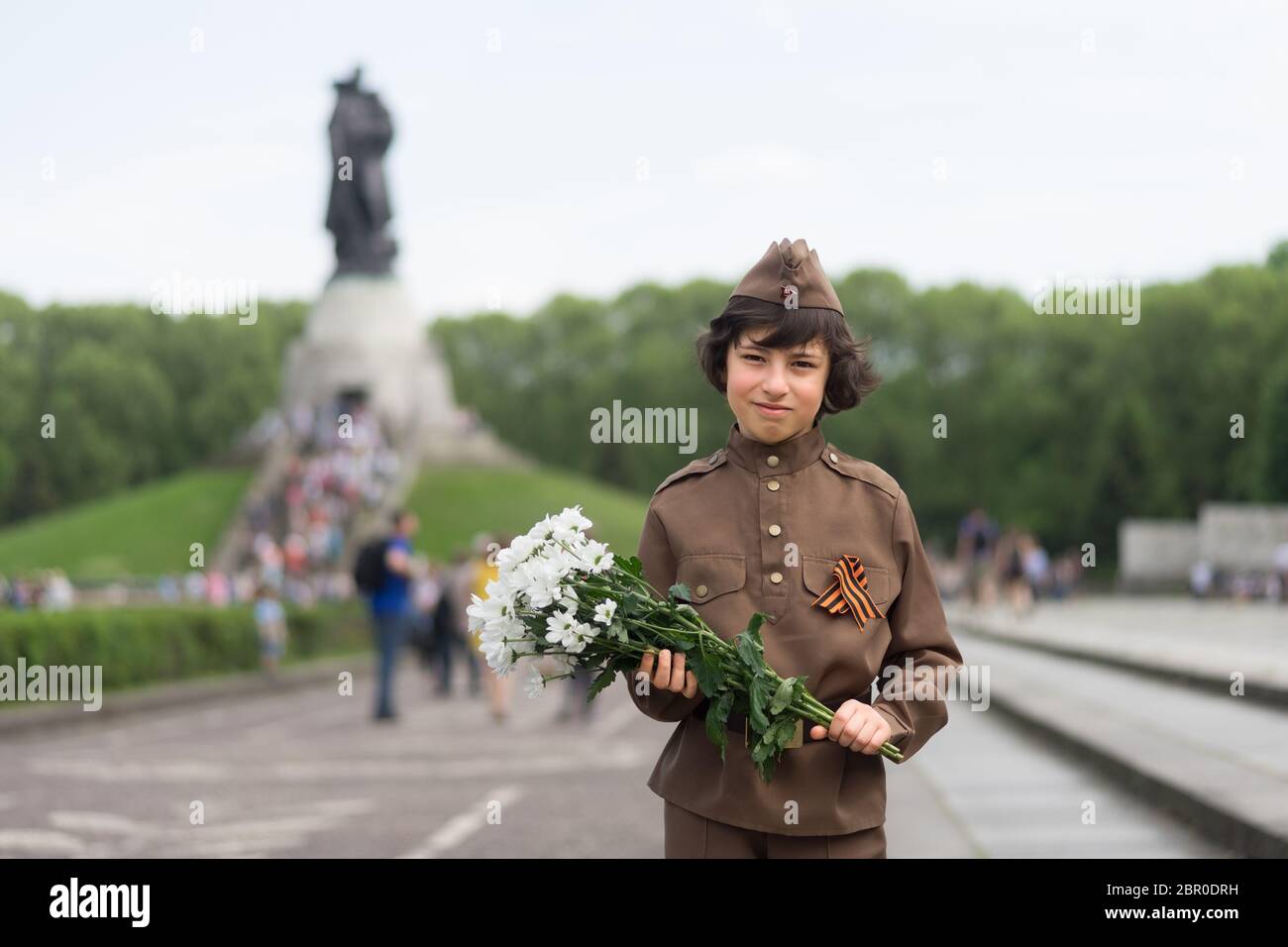 Portrait d'un garçon avec des fleurs, de l'uniforme d'un soldat de l'Armée rouge pendant la Seconde Guerre mondiale. Monument commémoratif de guerre soviétique (parc de Treptow), Berlin, Banque D'Images