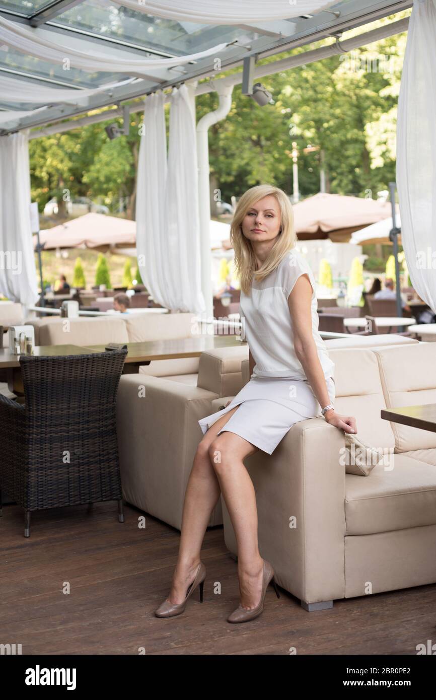 Belle femme blonde est assise dans un café d'été et repose Banque D'Images