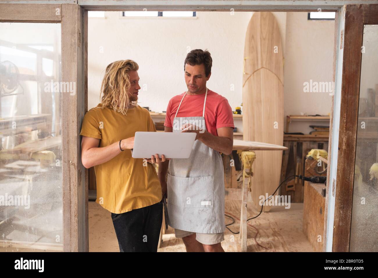 Deux hommes de surf caucasiens se tenant près du cadre de porte et travaillant sur des projets Banque D'Images