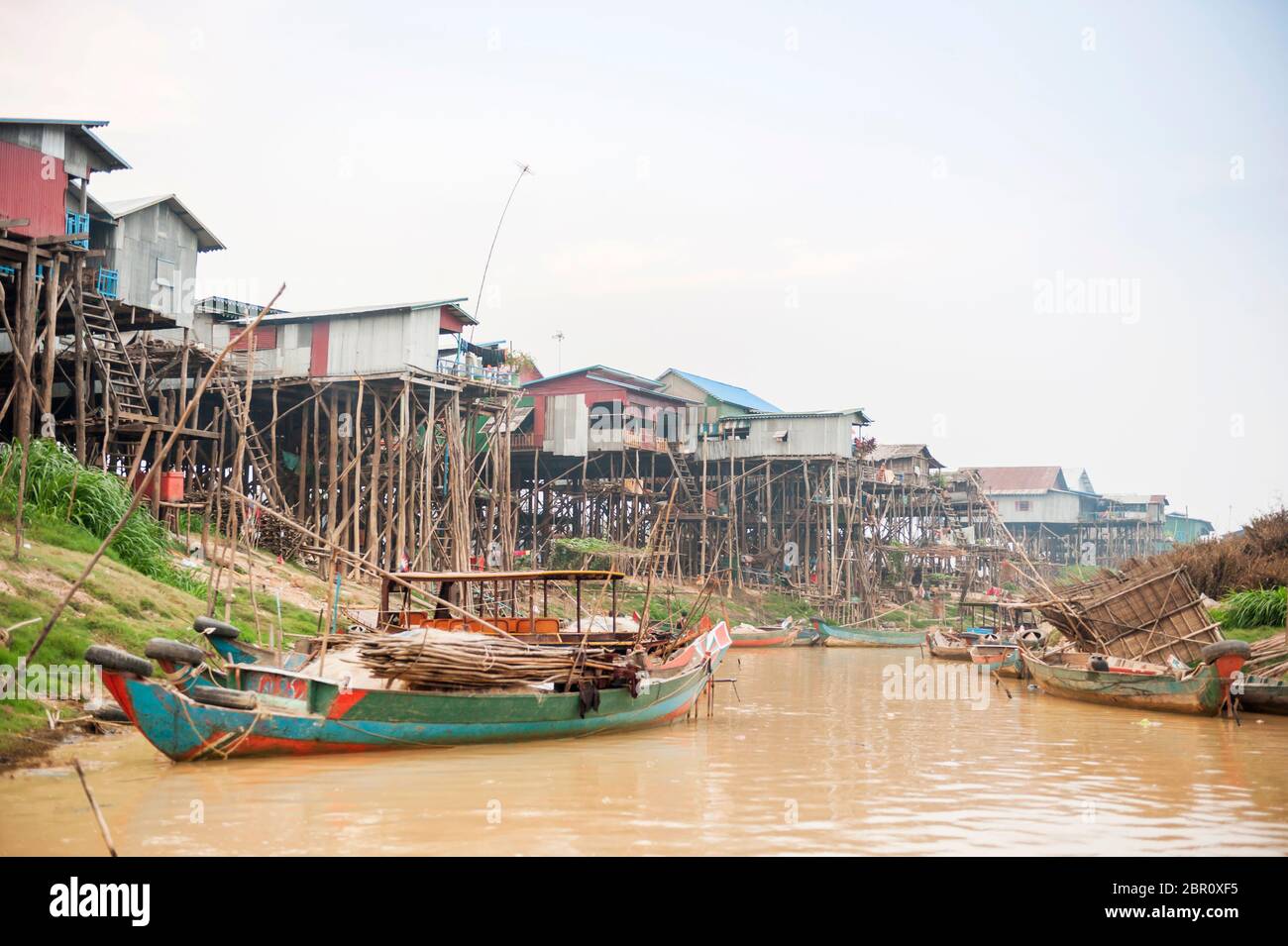 Bateaux sur la rivière avec des maisons sur pilotis en arrière-plan à Kampong Phluk, province de Siem Reap, centre-nord du Cambodge, Asie du Sud-est Banque D'Images