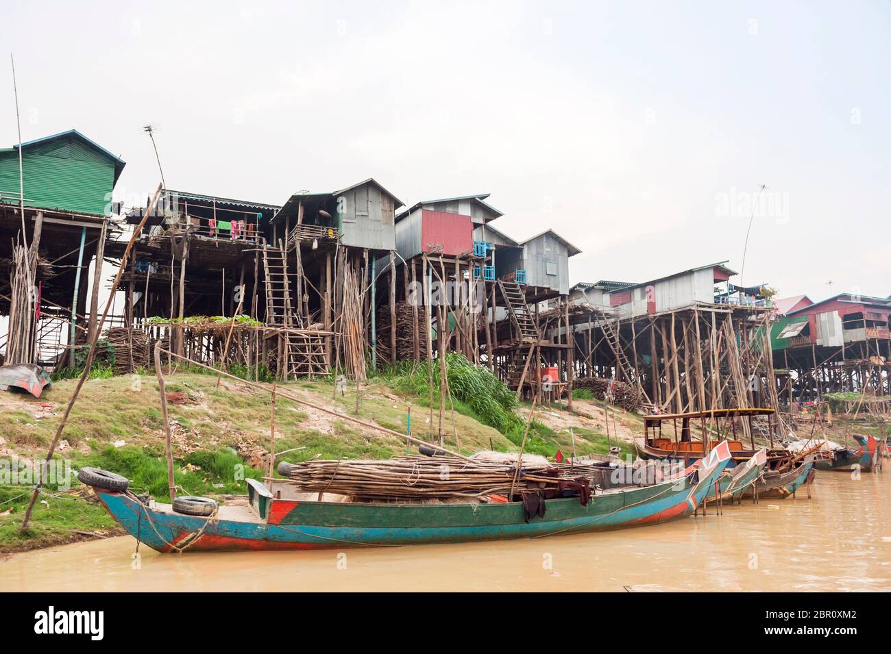 Bateaux sur la rivière avec des maisons sur pilotis en arrière-plan à Kampong Phluk, province de Siem Reap, centre-nord du Cambodge, Asie du Sud-est Banque D'Images