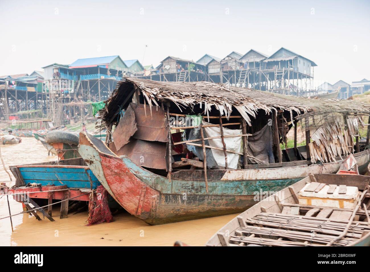 Bateaux sur la rivière avec des maisons sur pilotis en arrière-plan à Kampong Phluk, province de Siem Reap, centre-nord du Cambodge, Asie du Sud-est Banque D'Images
