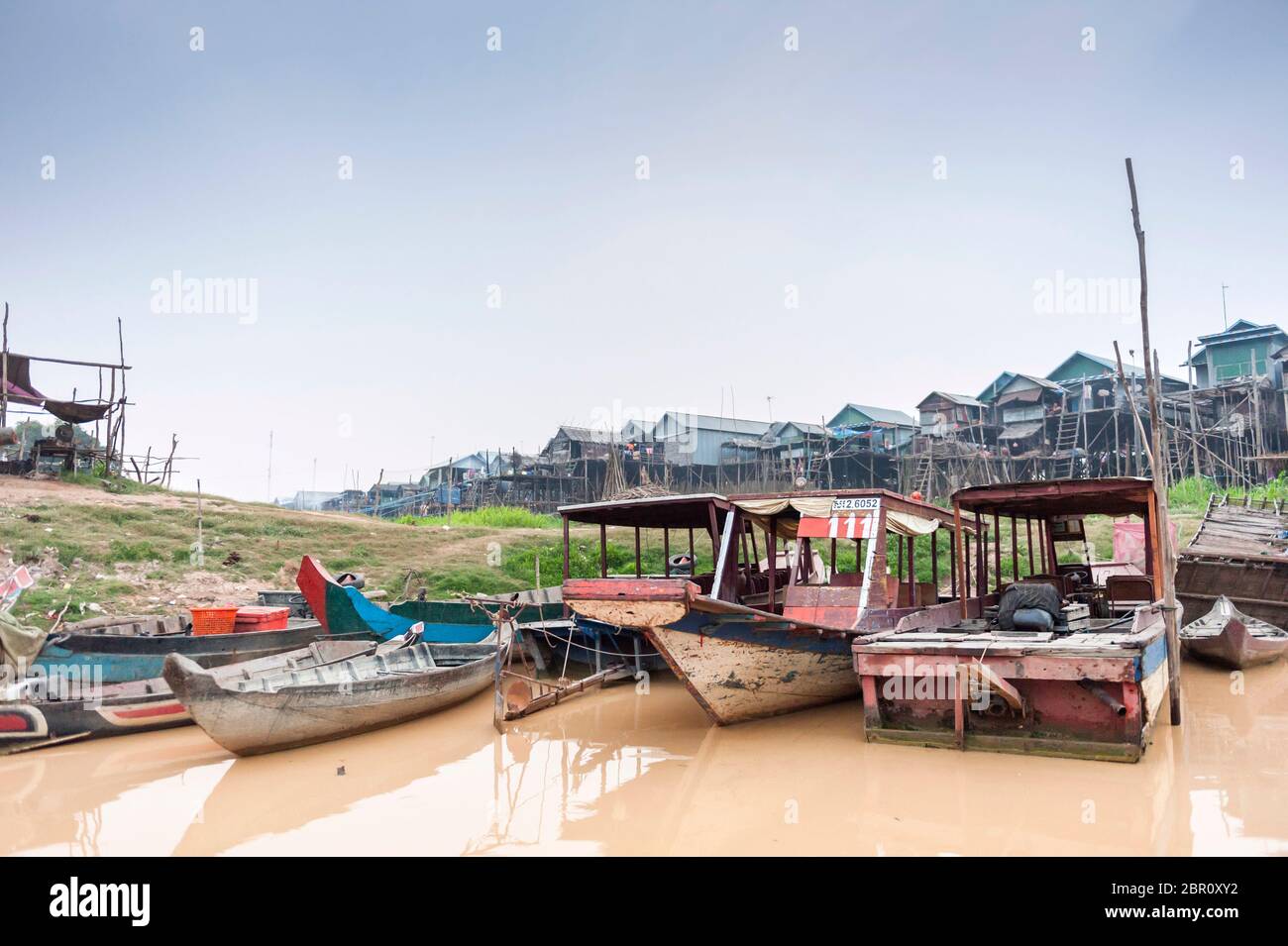 Bateaux sur la rivière avec des maisons sur pilotis en arrière-plan à Kampong Phluk, province de Siem Reap, centre-nord du Cambodge, Asie du Sud-est Banque D'Images