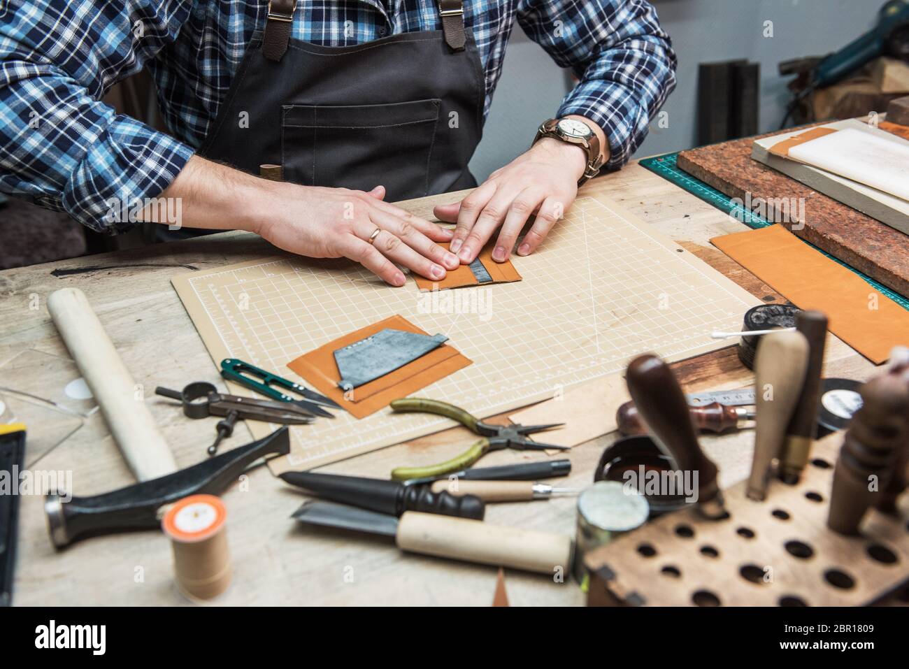 Travail avec le cuir homme lors d'un atelier textile. Concept de la production artisanale à la main des articles en cuir. Banque D'Images