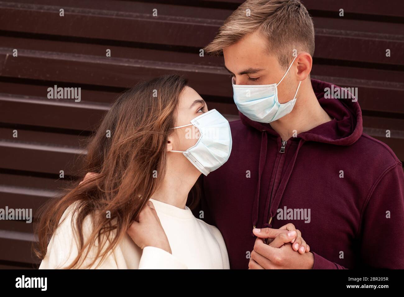 Jeune couple aimant portant des masques, embrassant et regardant les autres yeux Banque D'Images