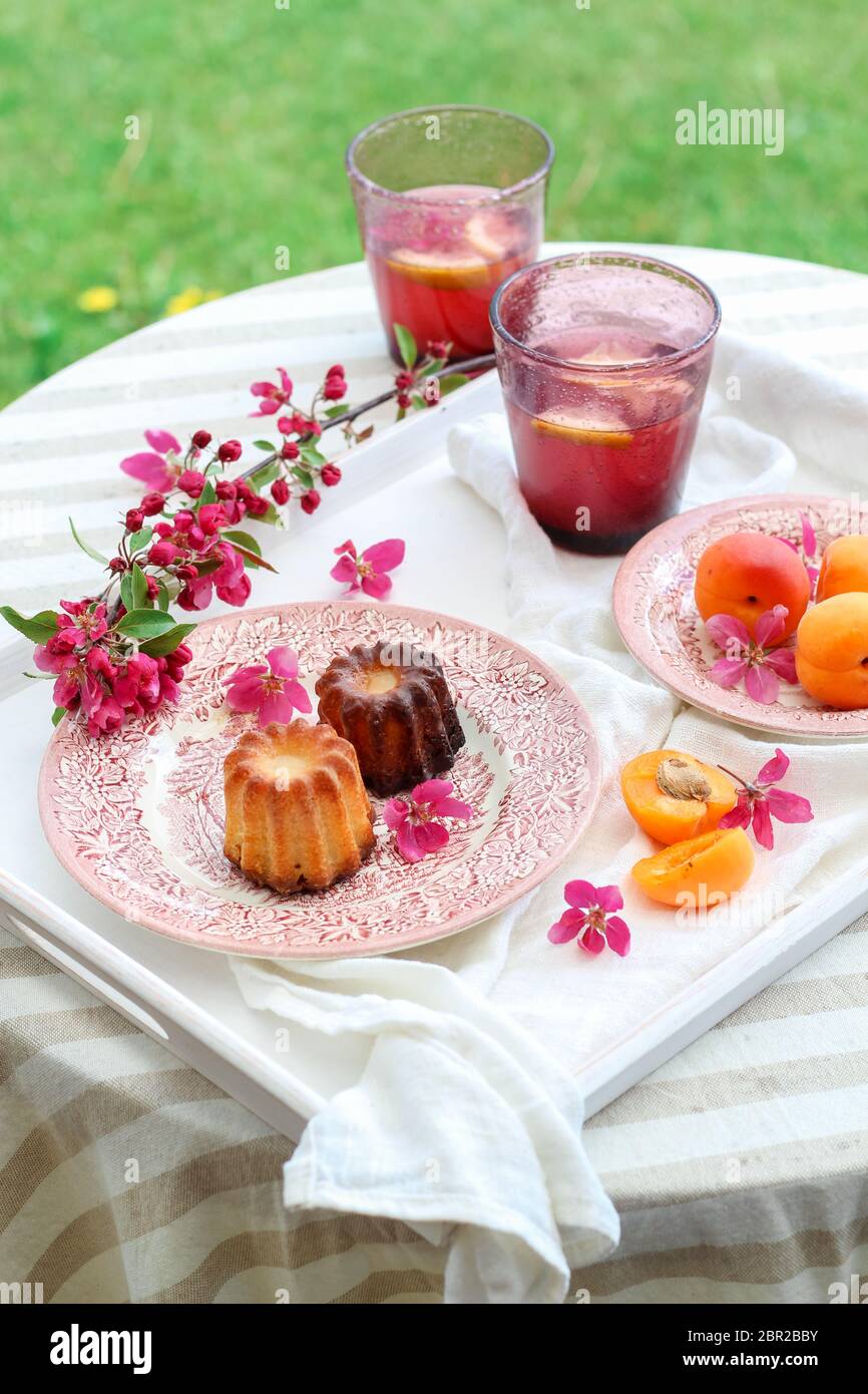 Table aux couleurs rose et pachy avec des caneles, des abricots et de la limonade maison Banque D'Images