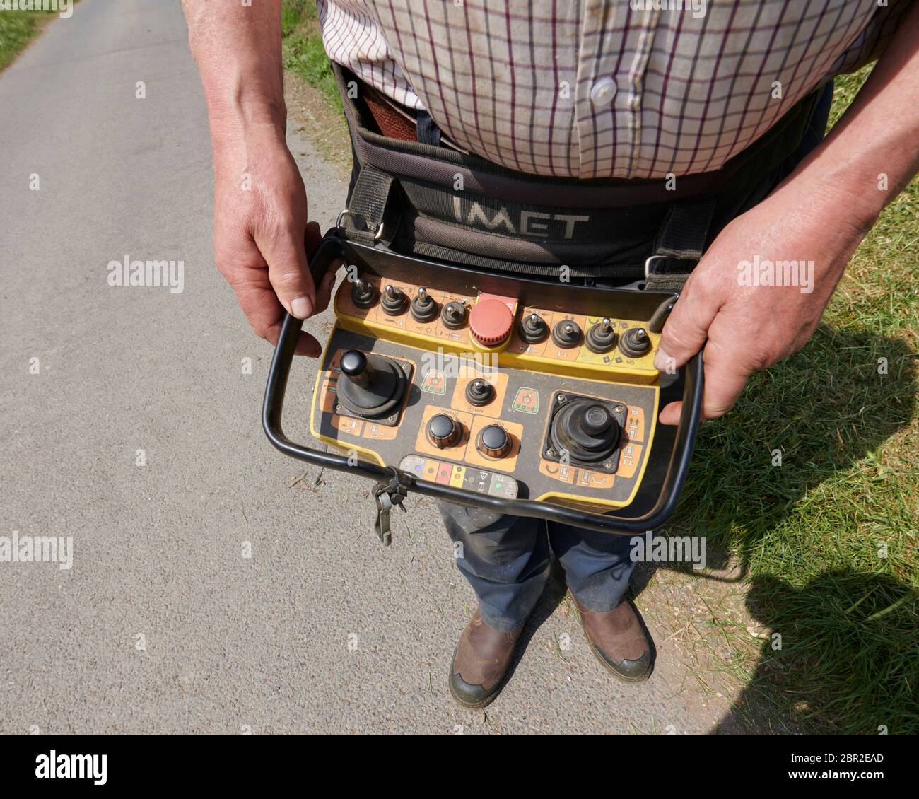 Homme utilisant une télécommande pour une machine de coupe d'herbe commerciale à distance, Angleterre, Royaume-Uni, GB. Banque D'Images