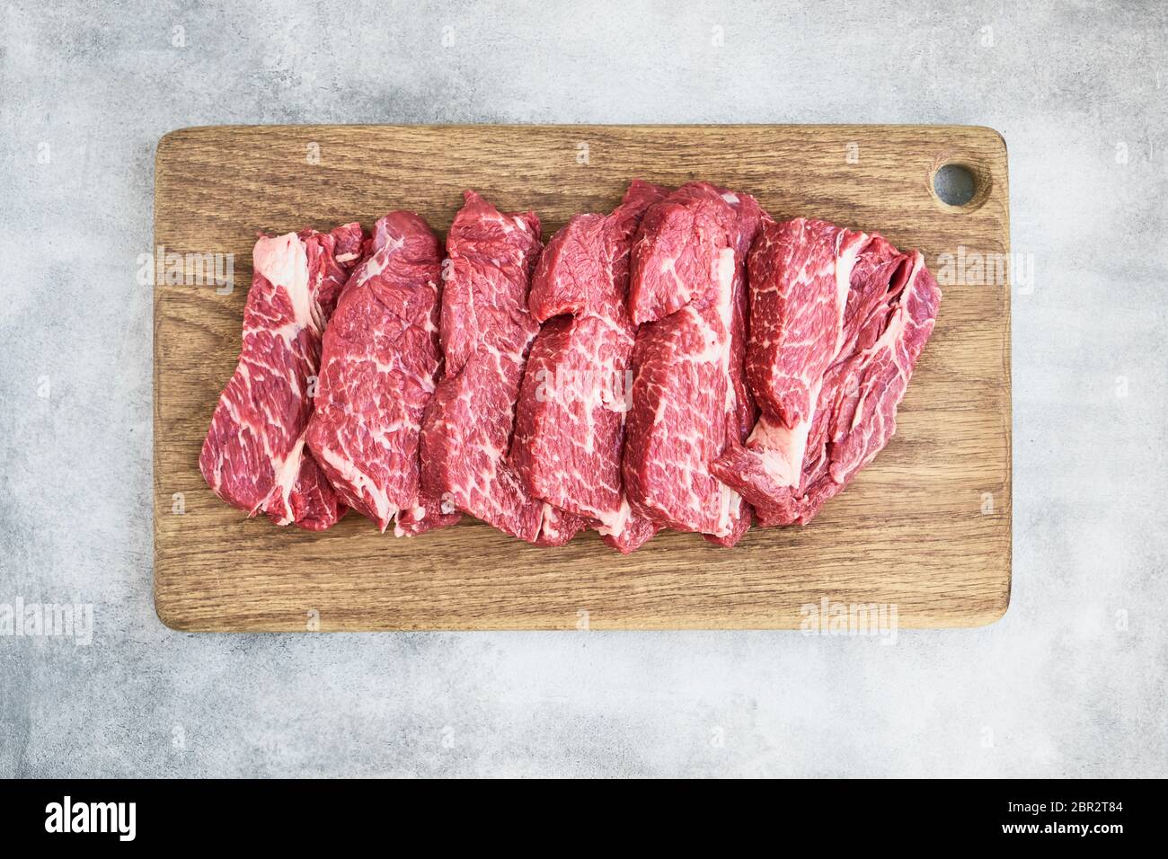 Steaks de bœuf frais sur planche à découper en bois sur fond gris. Copier l'espace pour le texte, vue de dessus. Banque D'Images