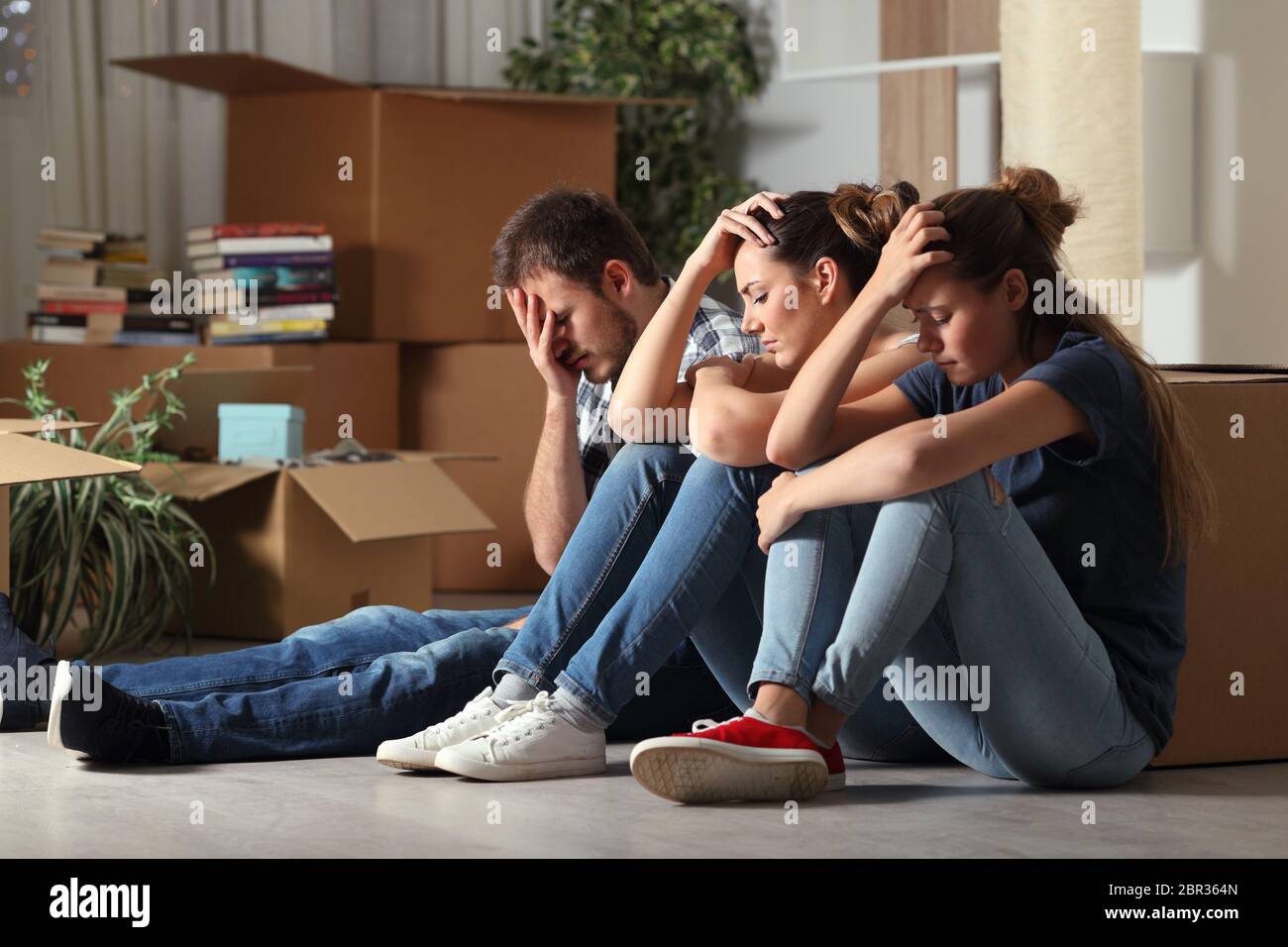 Triste trois colocataires expulsées déménagement accueil se plaindre assis sur le plancher Banque D'Images