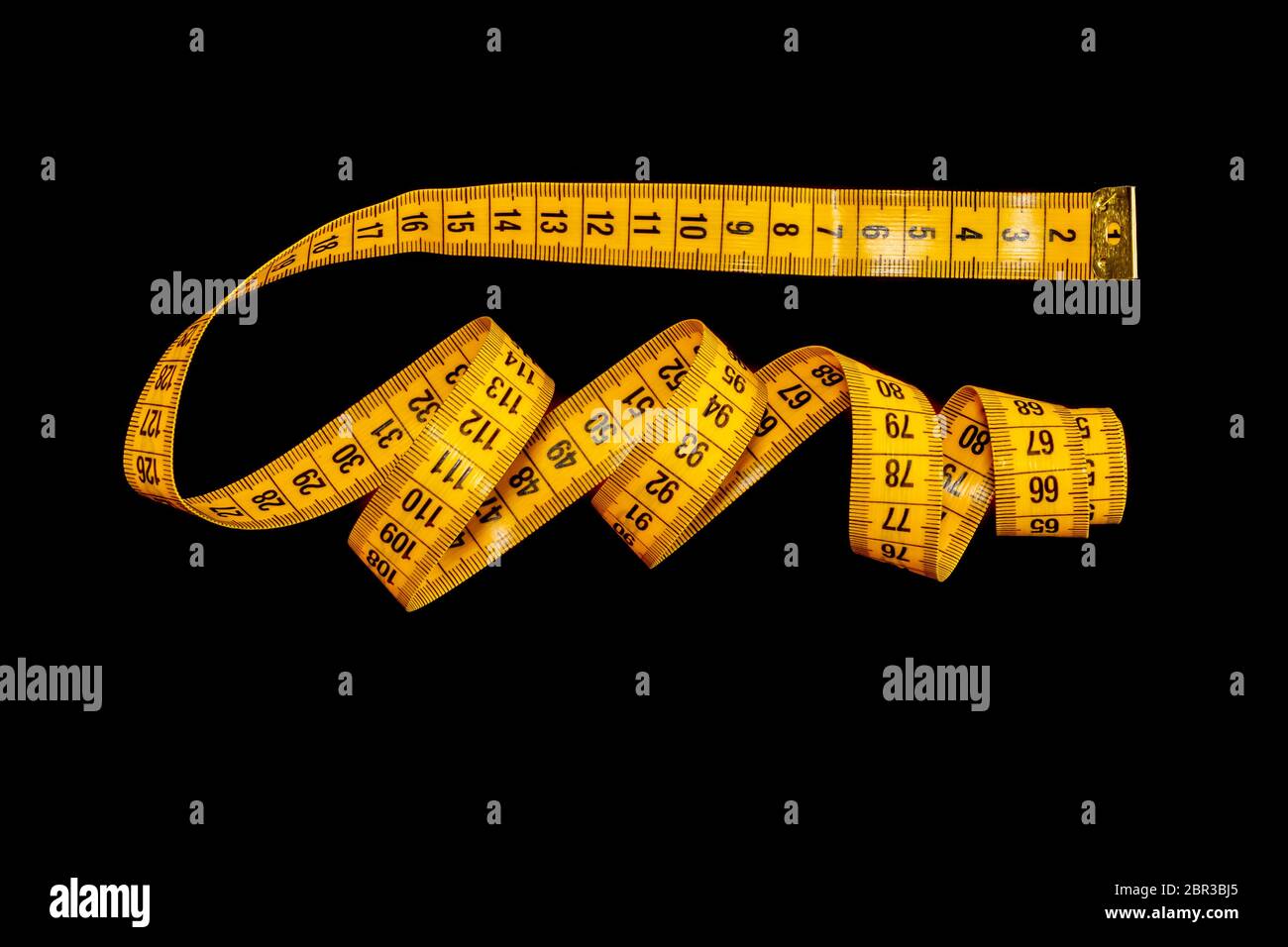 Ruban de mesure jaune isolé sur fond noir. Banque D'Images