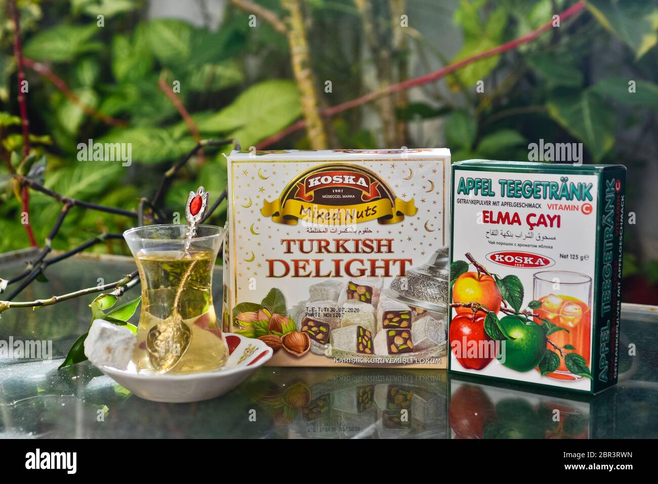 Thé turc aux pommes et bonbons (délices turcs), servis sur une table en verre dans un jardin Banque D'Images