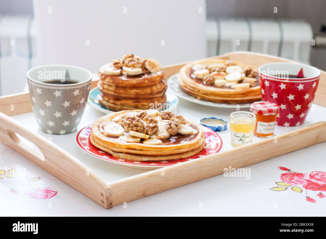Plateau de petit déjeuner avec crêpes aux bananes, sirop d'érable et noix, tasse de café et miel. Concept de la nourriture du matin. Banque D'Images Plateau de petit déjeuner avec crêpes aux bananes, sirop d'érable et noix, tasse de café et miel. Concept de la nourriture du matin. Banque D'Images