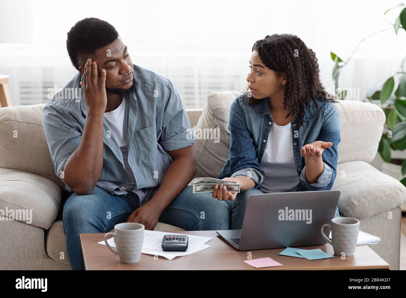 Couple comptable budget familial à la maison, femme qui colgne mari pour trop dépenser Banque D'Images