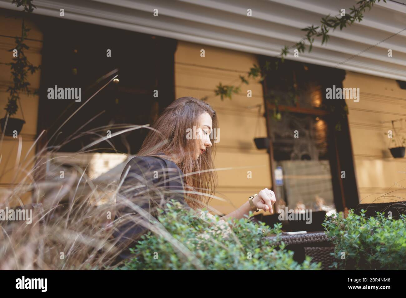 une dame solitaire regarde l'époque tout en étant assise à une table de restaurant Banque D'Images