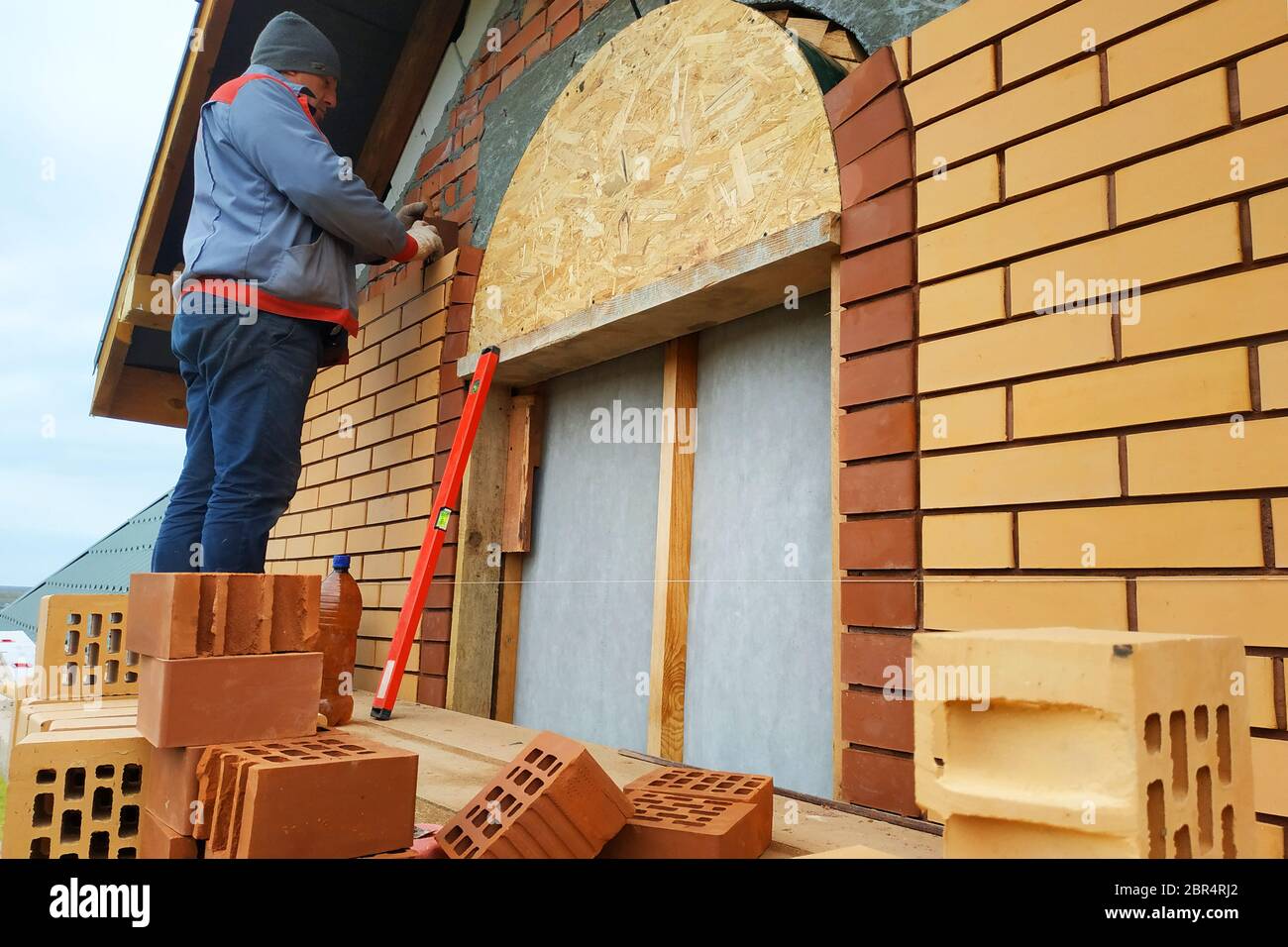 Le maître dans une combinaison bleue construit un mur de face brique.2020 Banque D'Images