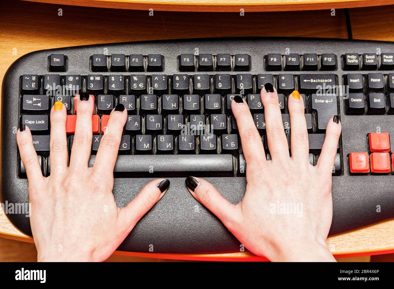 Les mains d'une femme sur un clavier d'ordinateur dans un bureau. Banque D'Images
