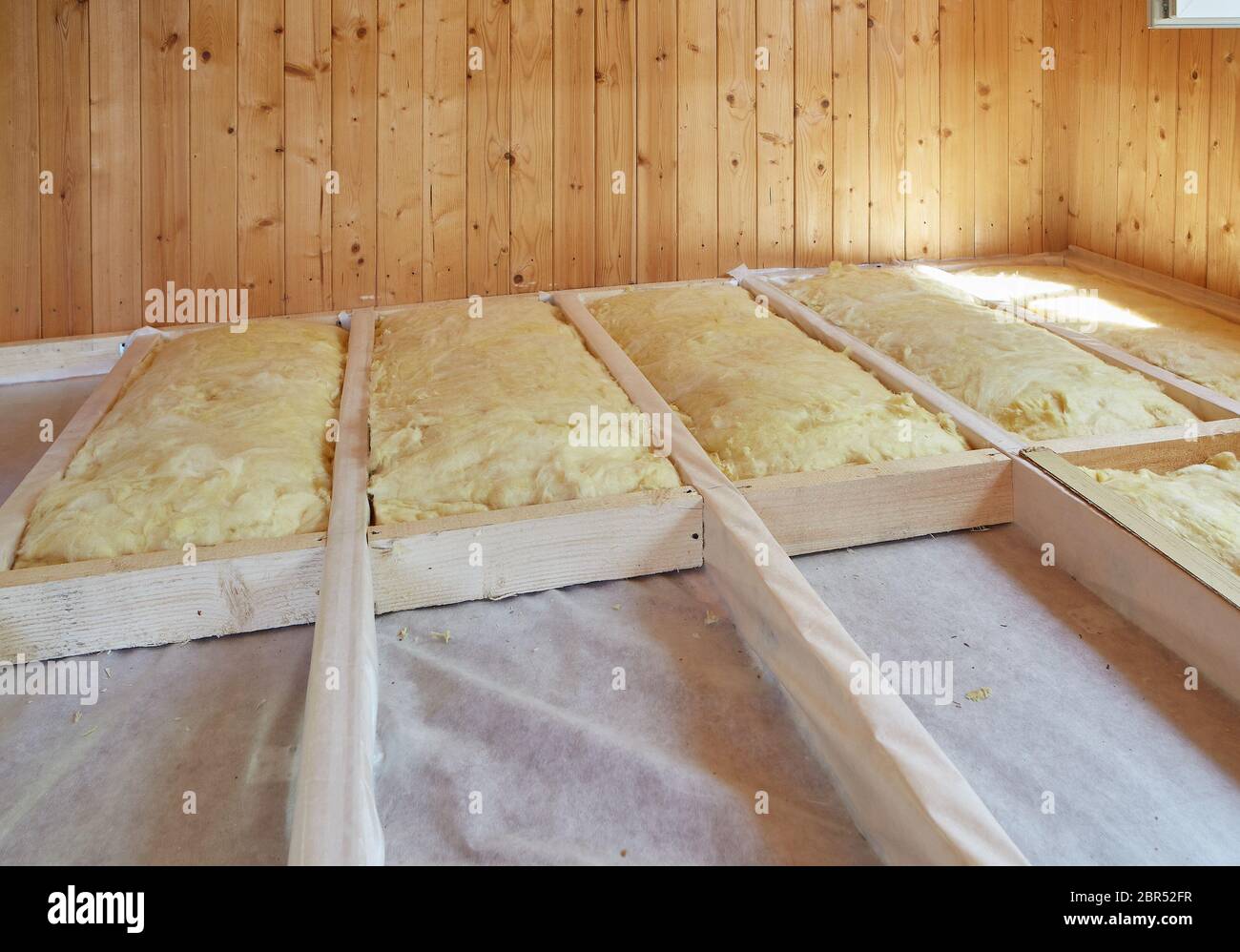 Pose de la couche d'isolation thermique sous le plancher avec de la laine minérale dans la chambre de la maison de campagne. Réchauffement d'un sol étape par étape. Banque D'Images