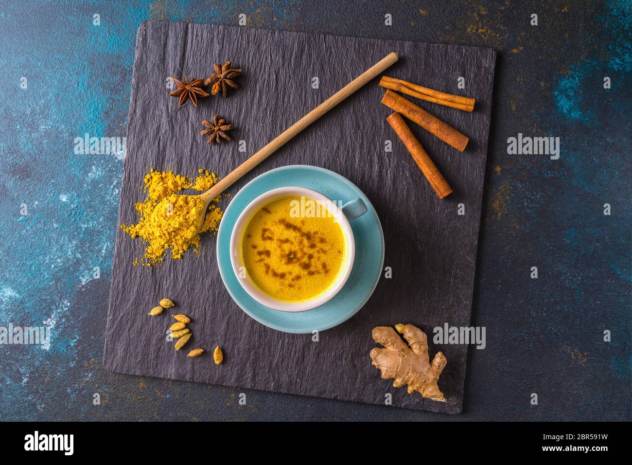 Thé au lait latte doré à base de curcuma et autres épices, sur fond de bois. Boisson saine. Pose à plat. Banque D'Images