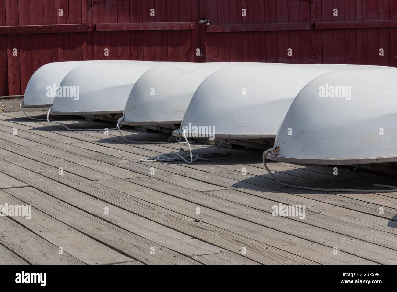 Coques blanches de petits voiliers à l'envers sur un quai en bois, arrière-plan de la tourbière rouge, aspect horizontal Banque D'Images