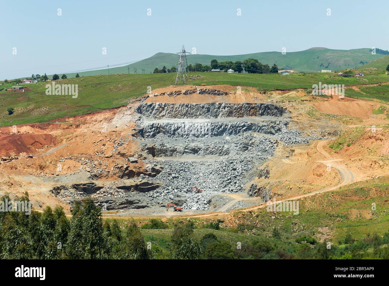 Carrière de roche en pierre à flanc de coteau avec machines industrielles. Banque D'Images