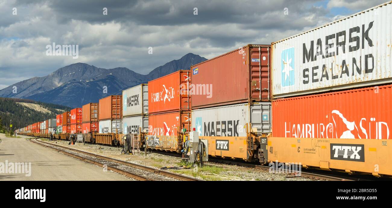 JASPER, ALBERTA, CANADA - JUIN 2018 : un long train de marchandises chargé de conteneurs d'expédition traversant Jasper, Canada. Banque D'Images