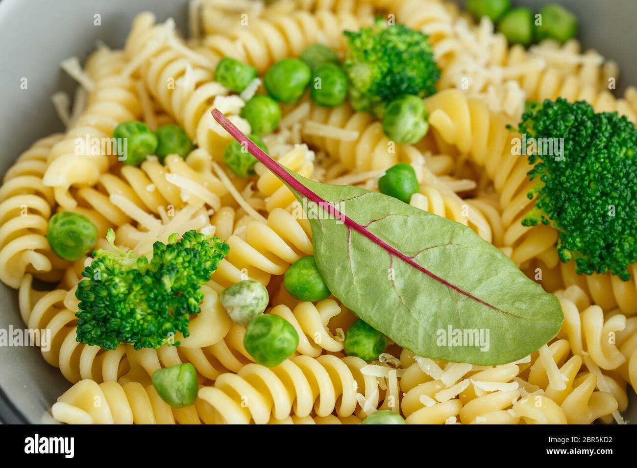 Pâtes aux légumes verts et au parmesan. Salade de pâtes de fusilli végétaliens au brocoli et aux pois verts Banque D'Images