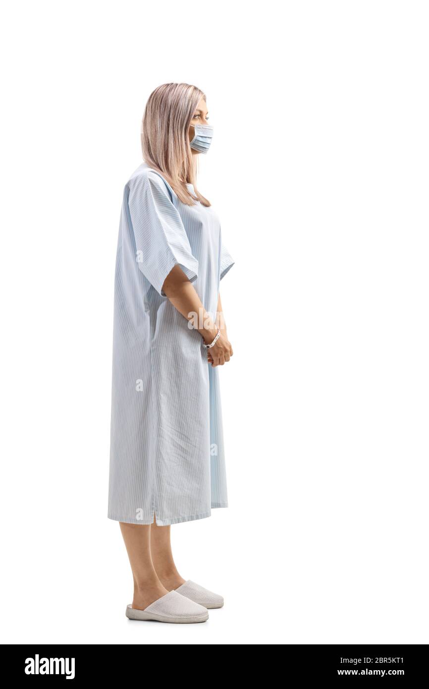 Prise de vue en profil d'une femme en robe de patient portant un masque de protection isolé sur fond blanc Banque D'Images