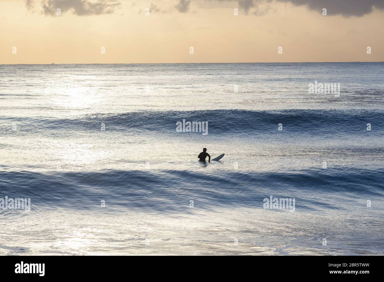 Surfer sur les vagues de l'océan a silhoueté matin séance de surf lever du soleil. Banque D'Images