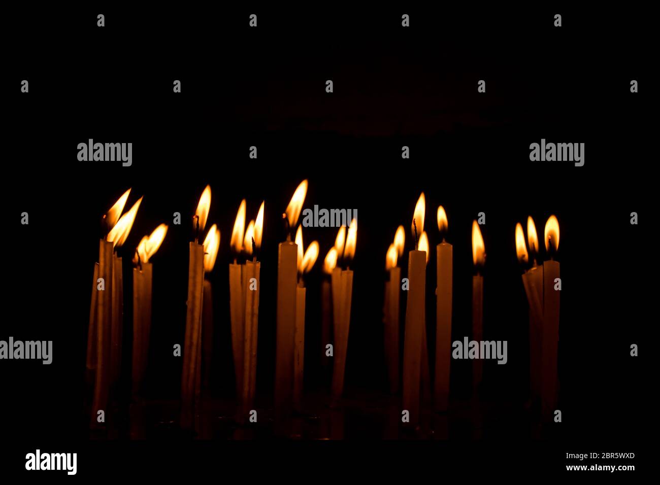 De nombreuses bougies de Noël dans la nuit sur le fond noir. Flamme de bougie set isolé en fond noir. Groupe de bougies allumées dans le noir avec Banque D'Images