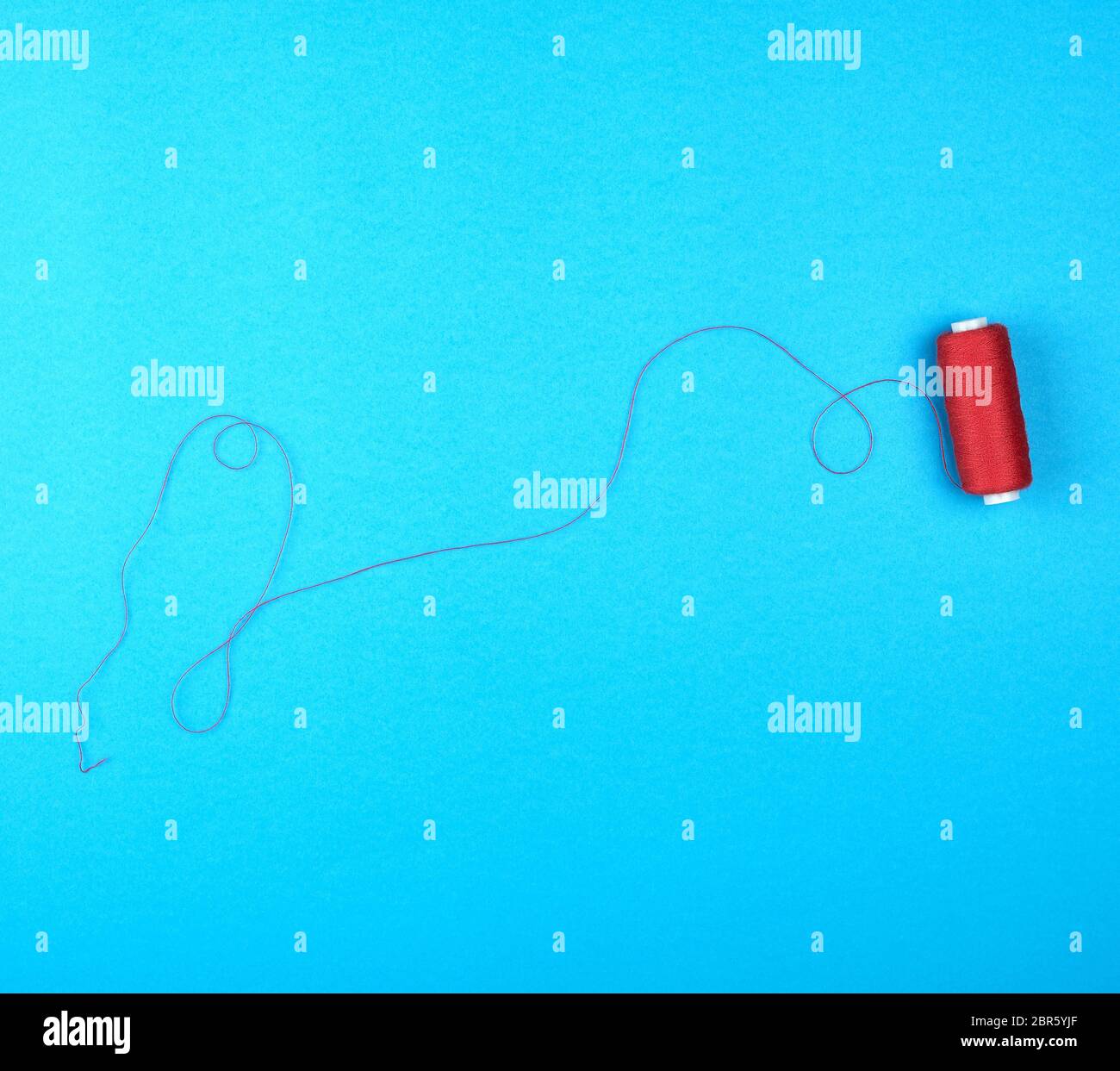 Bobine de fils rouges sur fond bleu, vue du dessus Banque D'Images