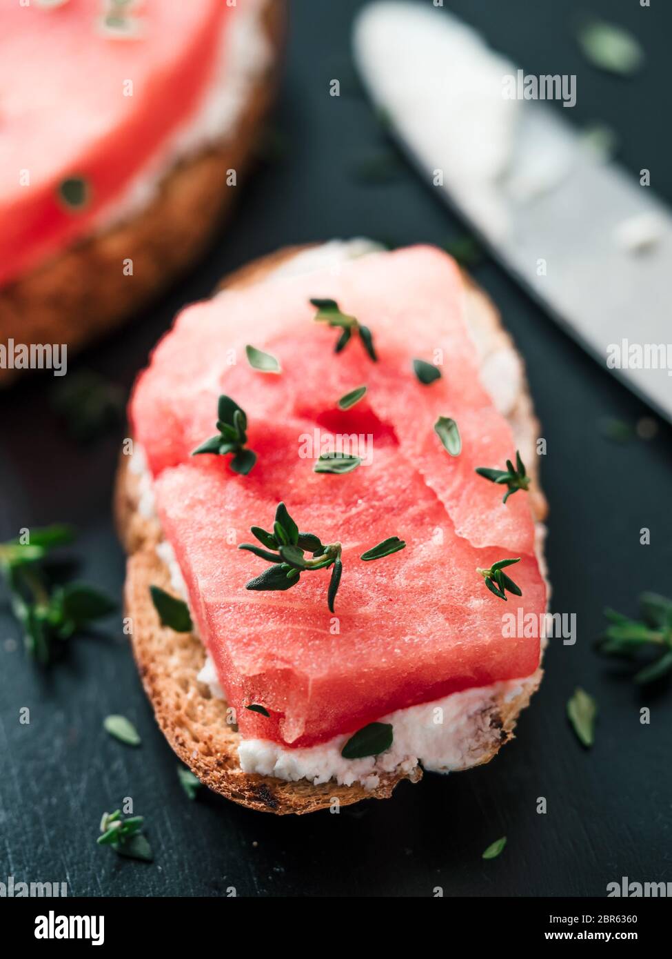 Toasts avec du fromage à pâte molle, de la pastèque et thym frais.salé sucré,fromage pastèque et épicé sur croquant de thym pain grillé tranches. Idée et recette pour Banque D'Images