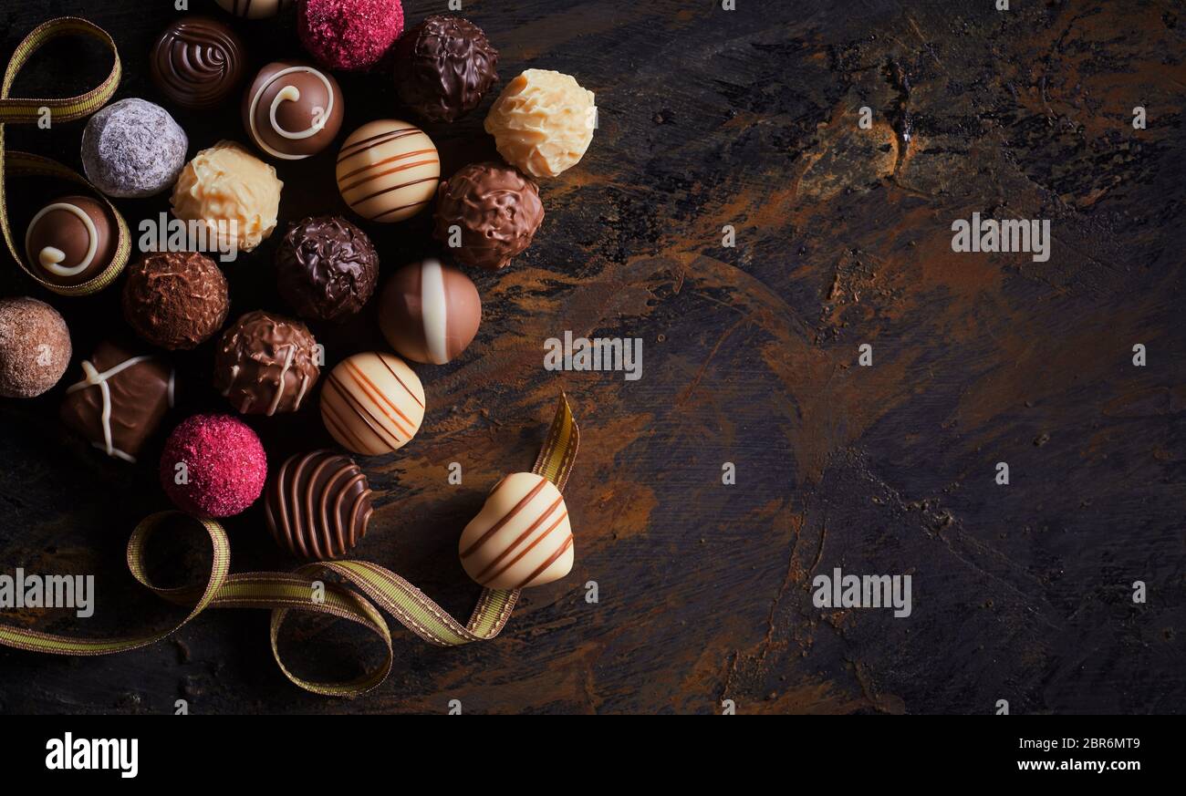 Bannière de luxe rustique avec des chocolats artisanaux et une praline en forme de cœur sur un ruban d'or plus virevoltante bois texturé avec vignette et copy space Banque D'Images