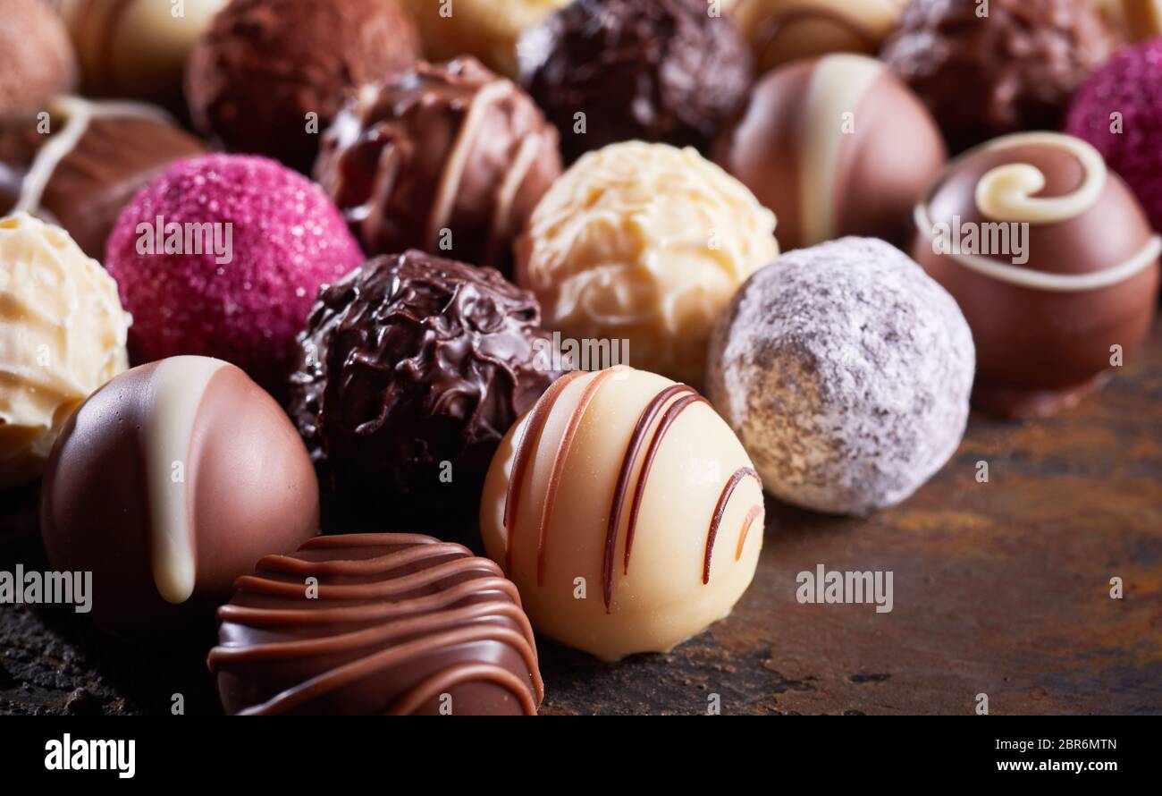 Close up detail d'une luxe ball chocolat blanc dans une grande sélection de chocolats ou les pralines sur bois rustique Banque D'Images