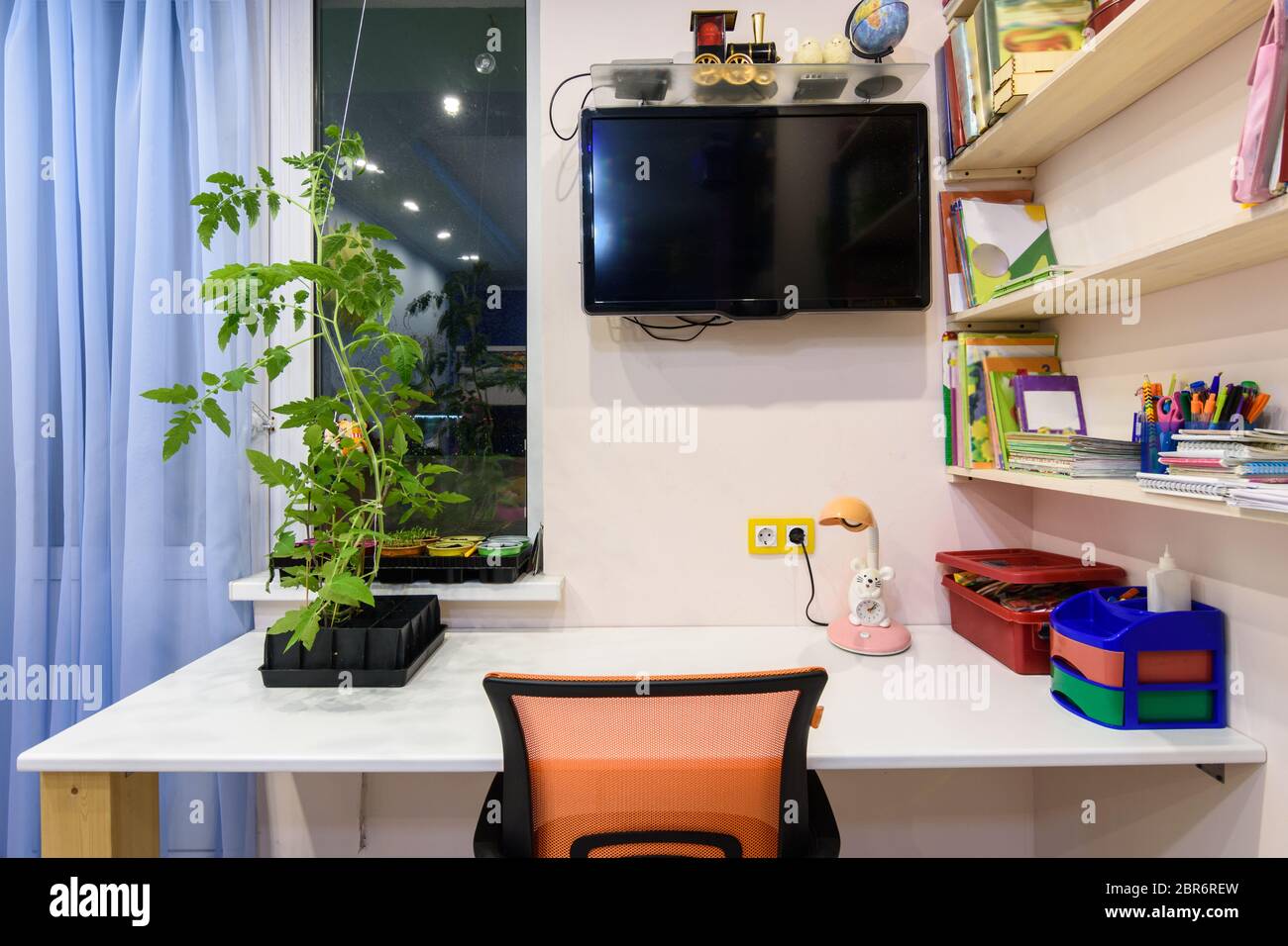 Un bureau dans la chambre des enfants, une télévision au mur et des étagères pour les livres scolaires Banque D'Images