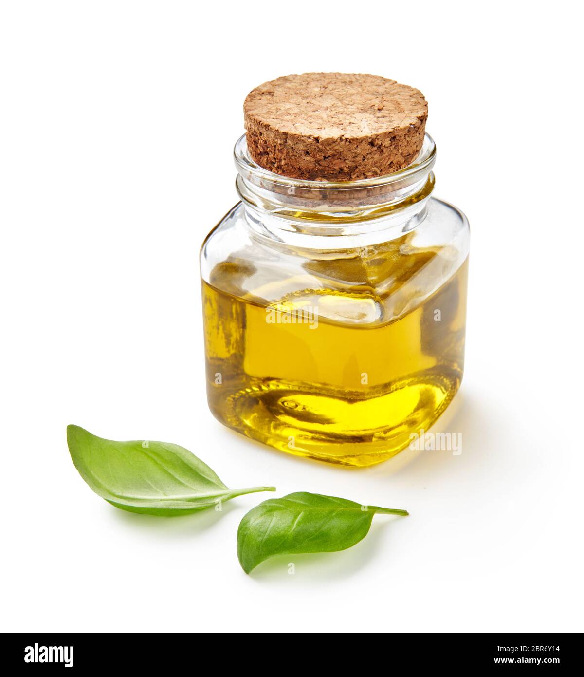 Pot en verre d'huile d'olive ou végétale avec feuilles de basilic isolées sur blanc. Banque D'Images