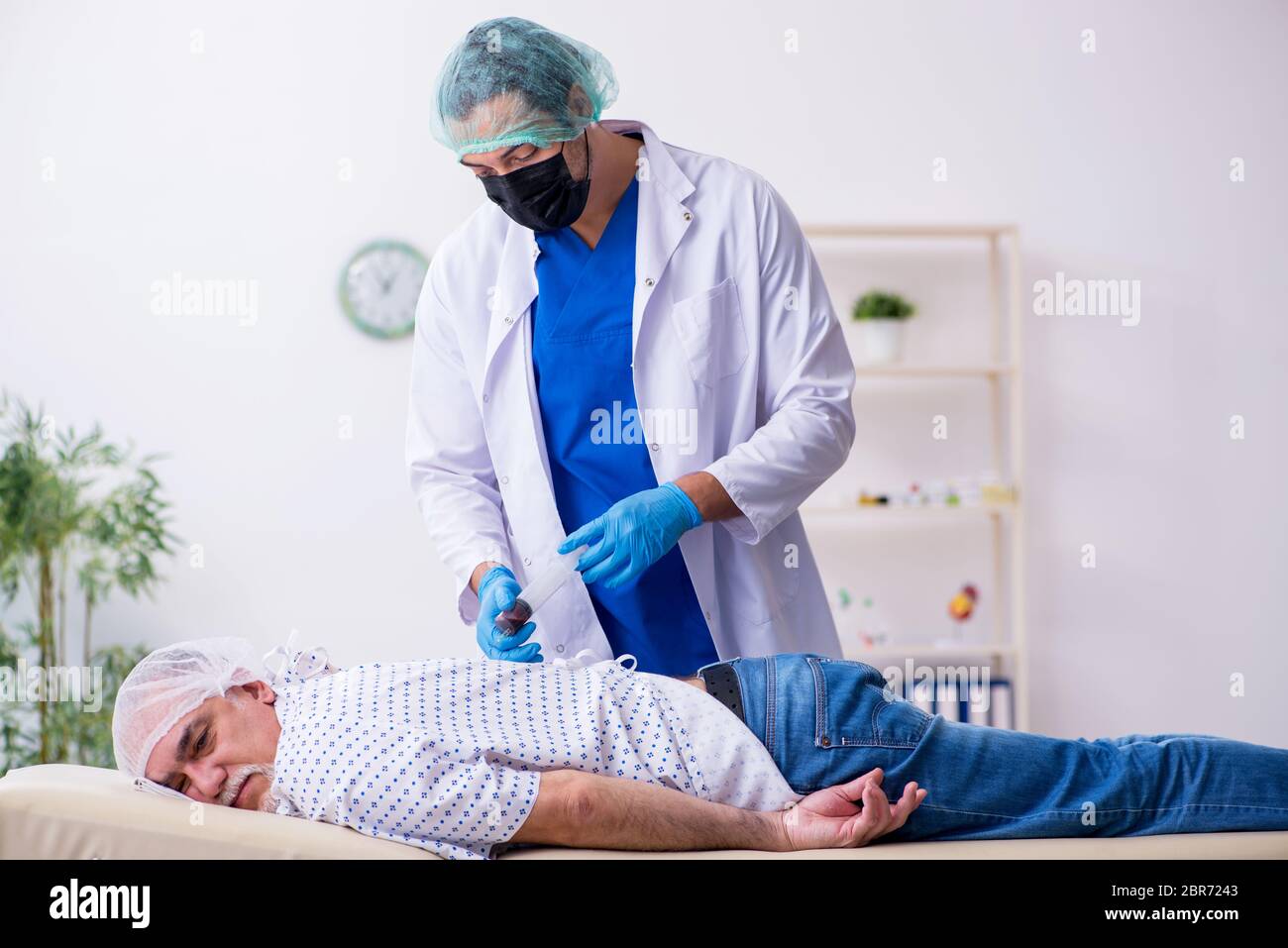 Un vieil homme qui rend visite à un jeune médecin stagiaire Banque D'Images