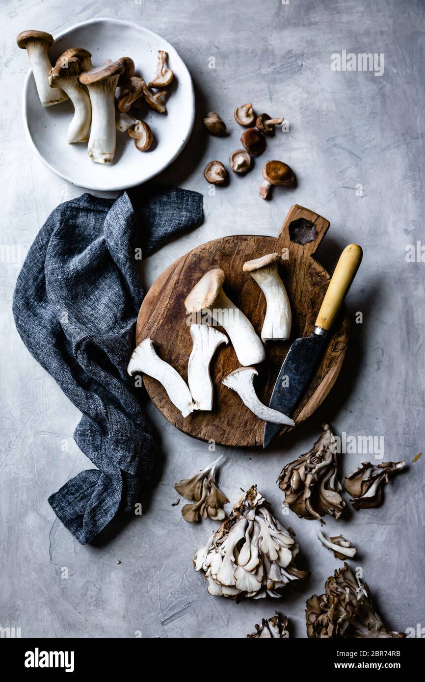Trompette et champignons maitake sur une planche à découper en bois. Banque D'Images