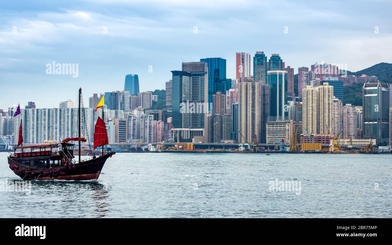 Jonque traditionnelle Chinoise en face de l'île de Hong Kong sur les toits de la ville avec des gratte-ciel Banque D'Images