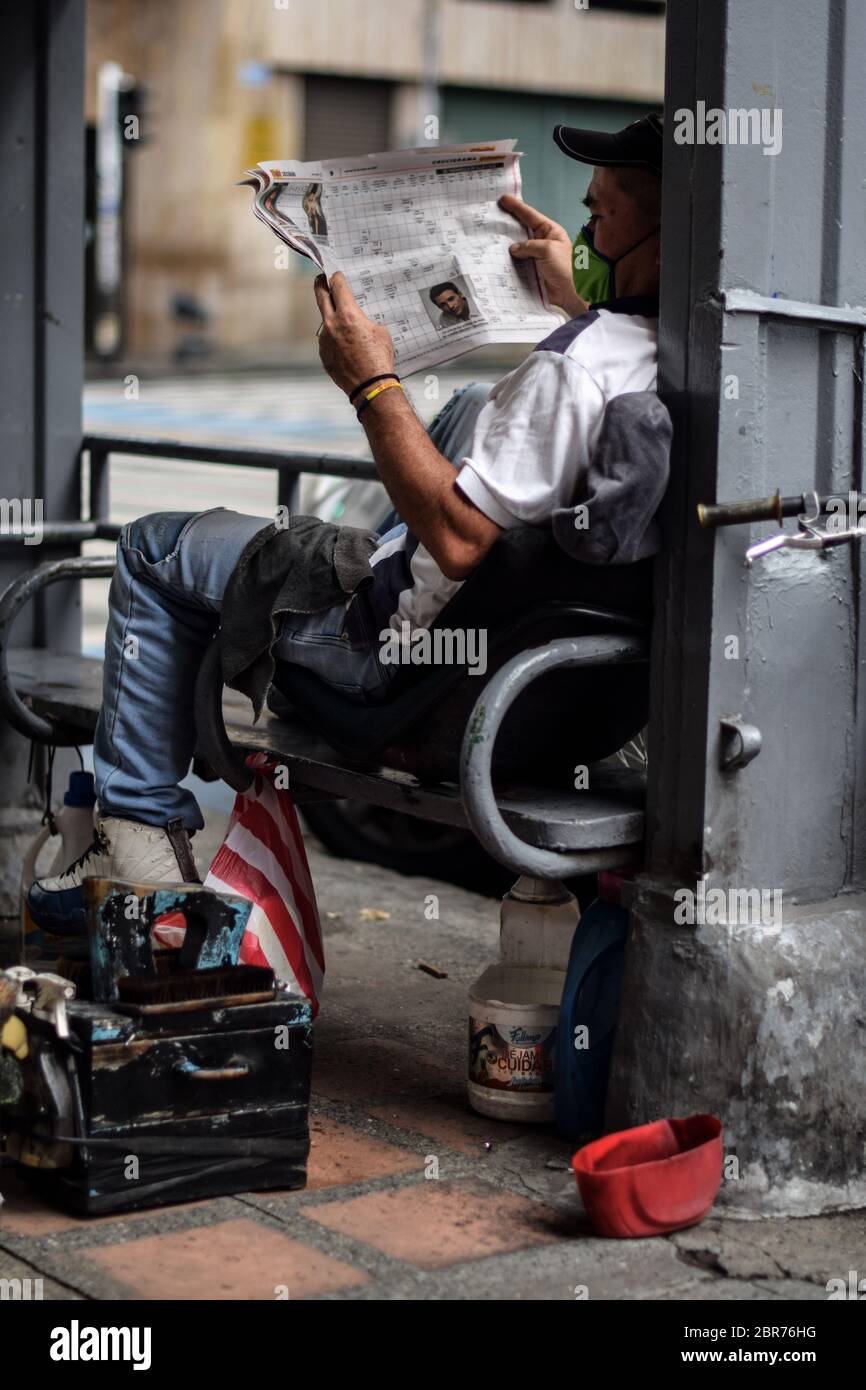 Le nettoyeur de chaussures lit les journaux dans le centre-ville pendant l'épidémie de coronavirus en Colombie Banque D'Images