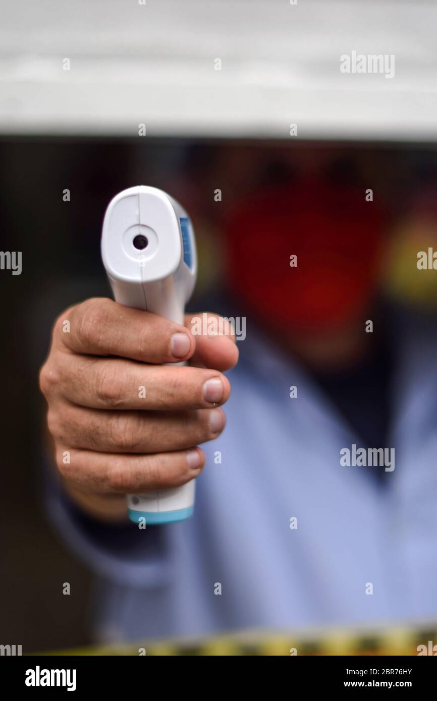 Ouvrier de magasin pointant thermomètre pistolet avant d'entrer dans le local, Colombie Banque D'Images