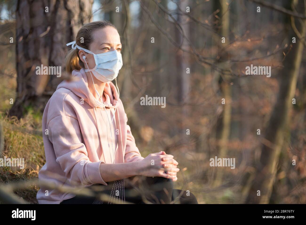 Portrait d'une femme sportive caucasienne portant un masque de protection médicale tout en se relaxant dans la nature et en écoutant de la musique. Le virus Corona, ou Covid-19, est Banque D'Images