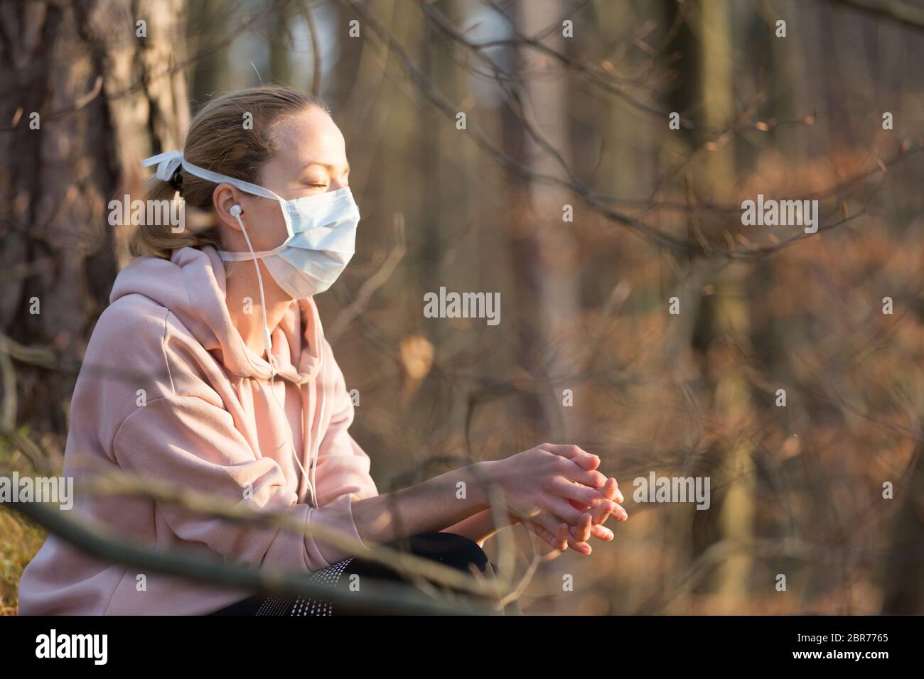 Portrait d'une femme sportive caucasienne portant un masque de protection médicale tout en se relaxant dans la nature et en écoutant de la musique. Le virus Corona, ou Covid-19, est Banque D'Images