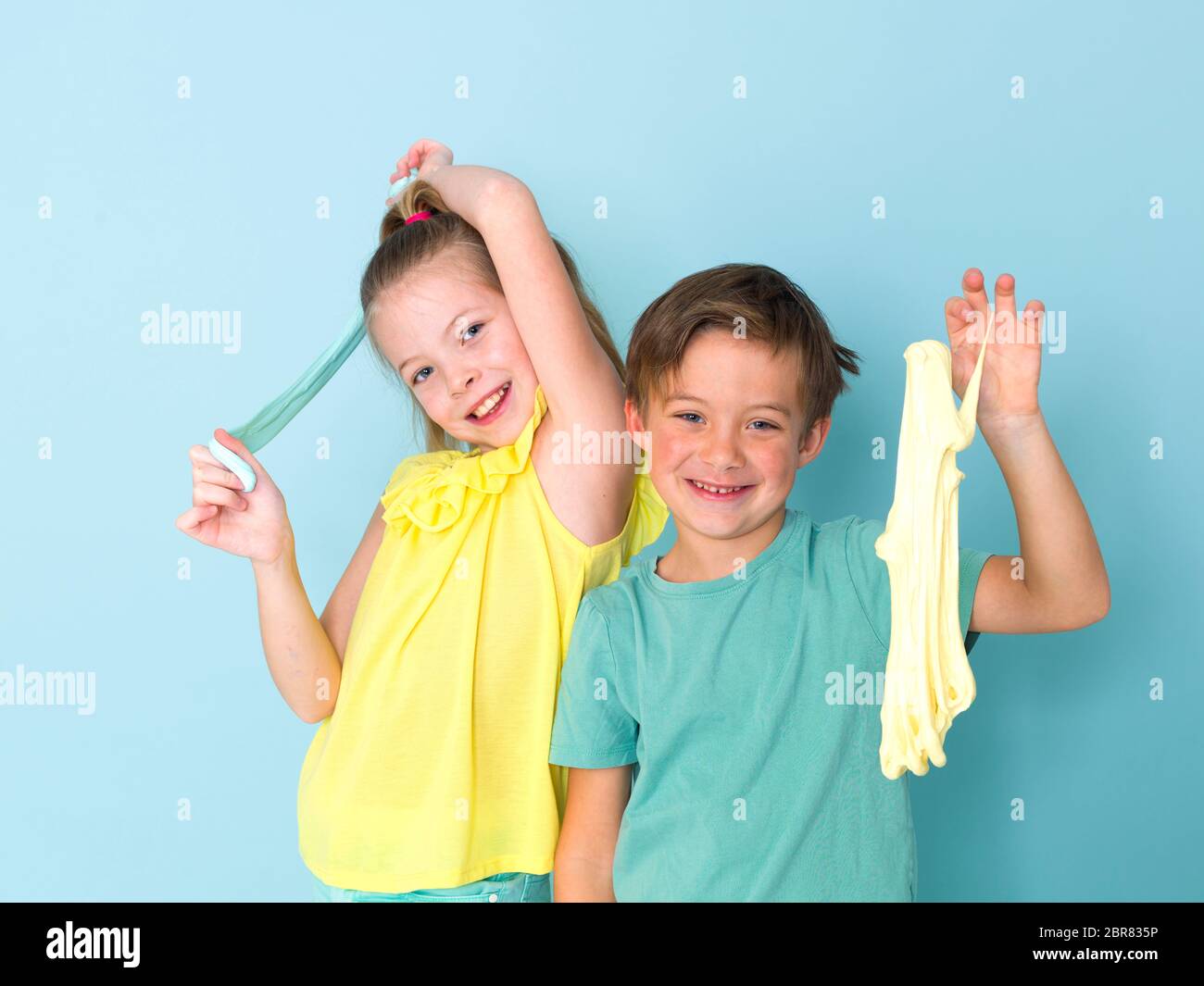 Cool, joli garçon et sa grande sœur jouent avec des dépôts devant un fond bleu et ayant beaucoup de plaisir Banque D'Images